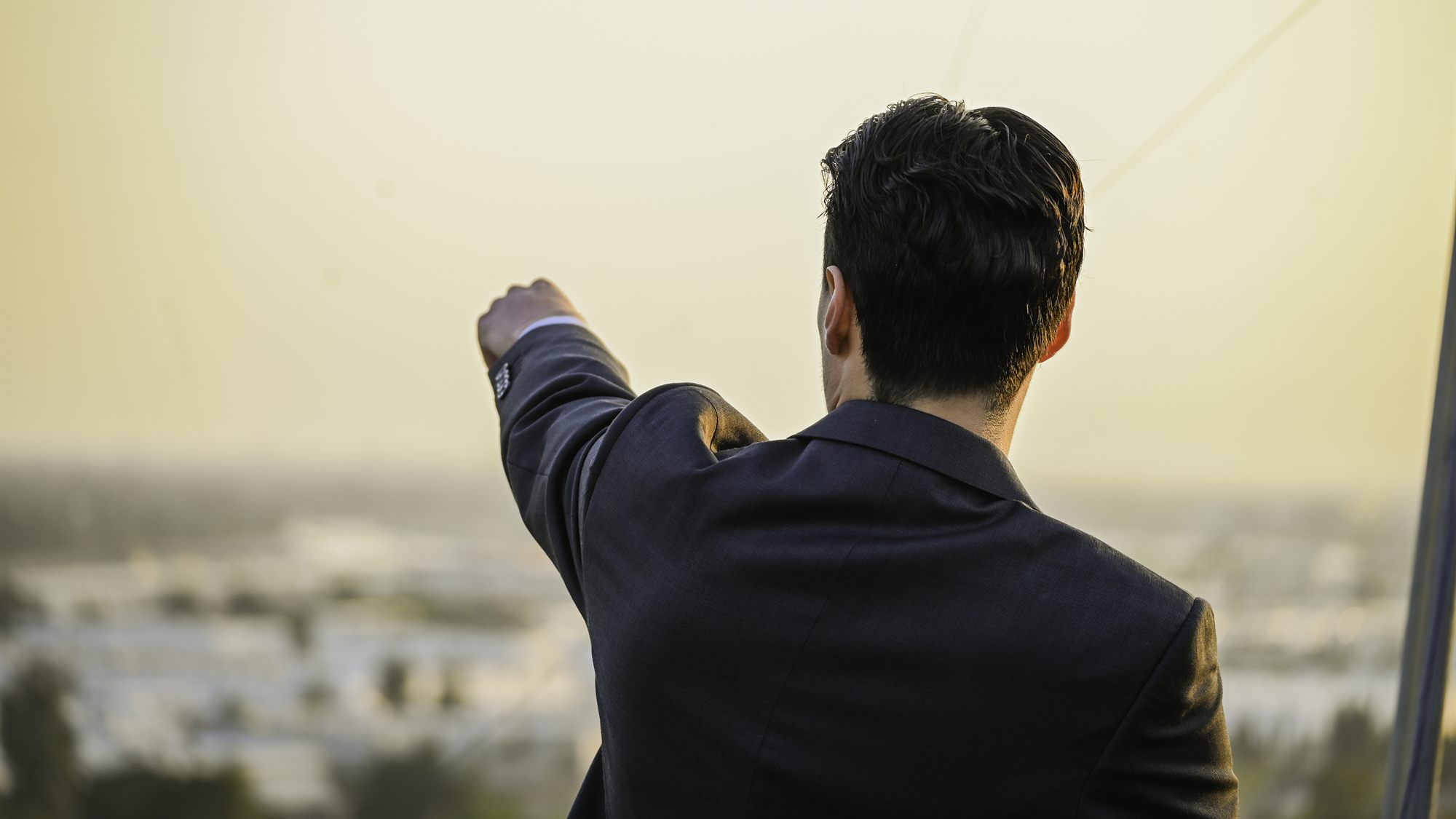 A member in a suit pointing out over the hazy Orange County skyline at dusk