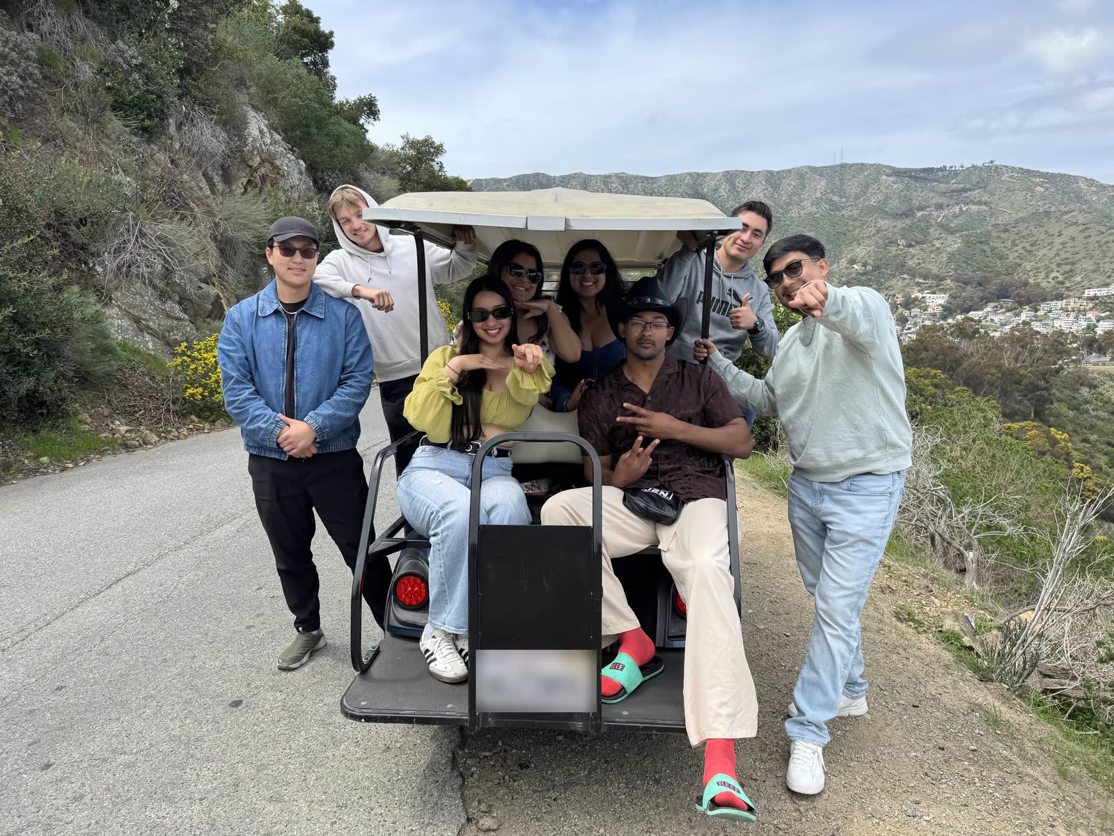 Members crowded onto a golf cart on a hillside road during a Catalina Island trip