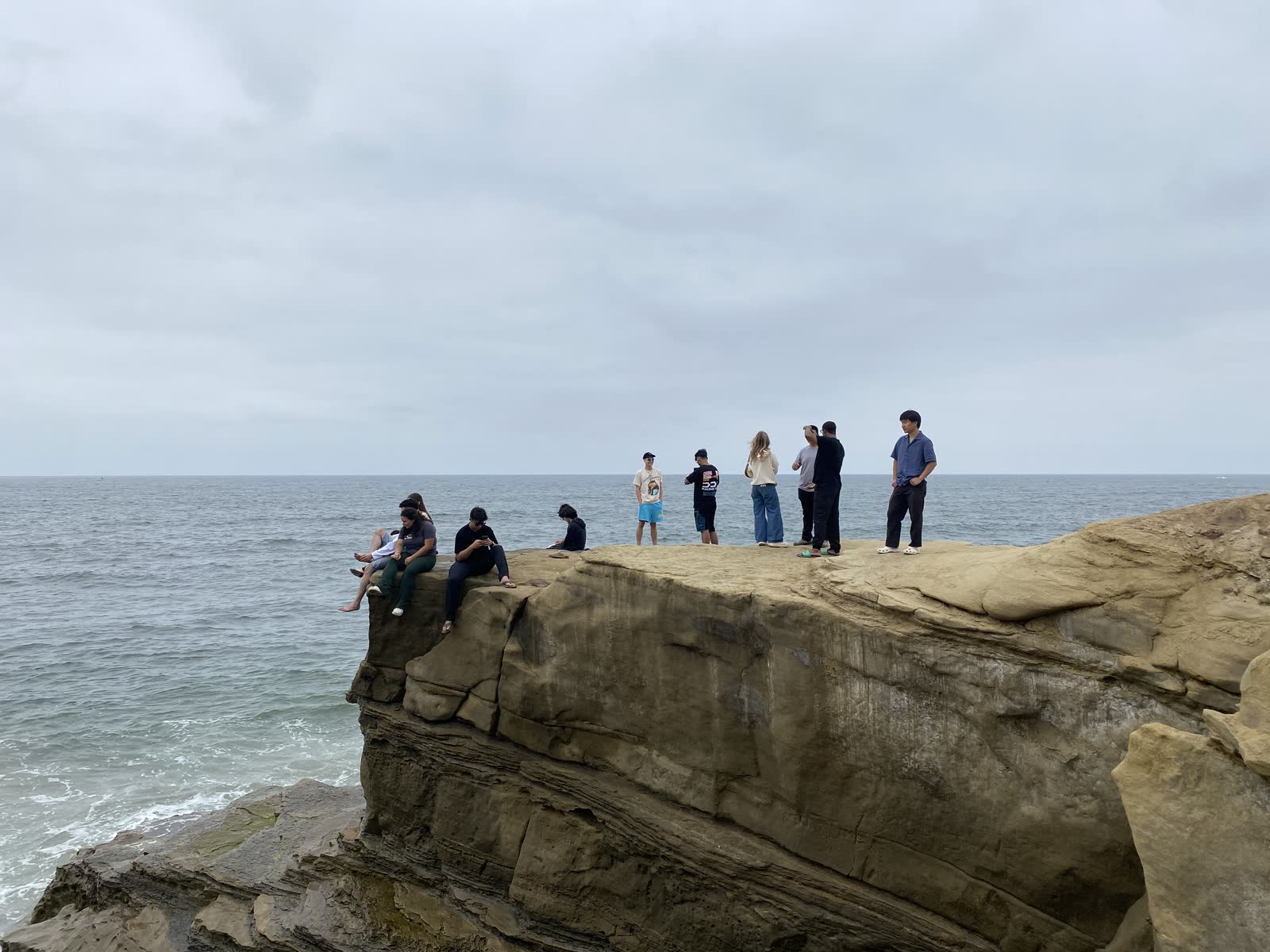 Members standing on an ocean bluff at Sunset Cliffs under an overcast sky