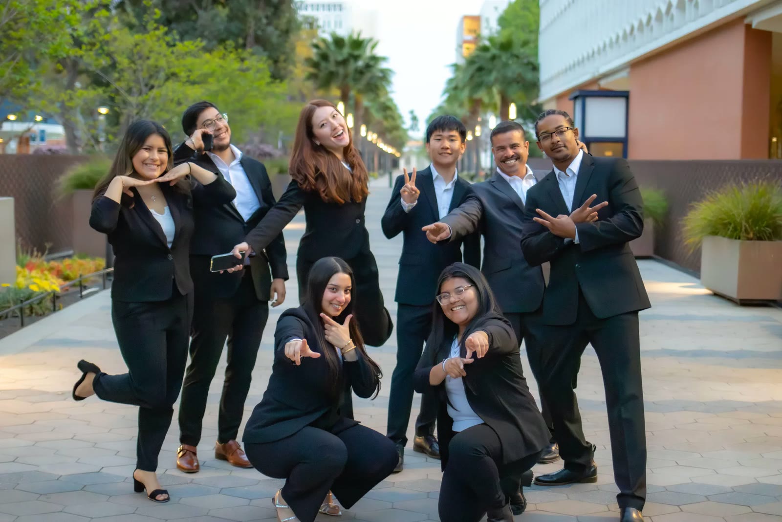 Members in business formal laughing and posing together on a downtown promenade at dusk