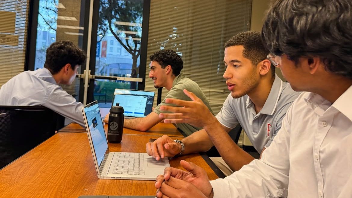 Four members working over laptops around a table during an evening session